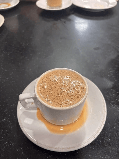 Cardamom tea in a white cup and saucer at a Bombay Hotel in Kozhikode.