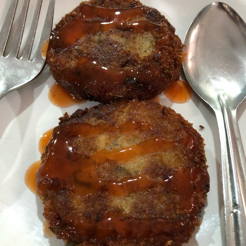 Bombay Hotel Kozhikode: Two crispy cutlets drizzled with sauce.