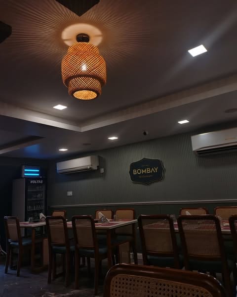 Bombay Hotel Kozhikode: Indoor seating with AC section and rattan lamps.