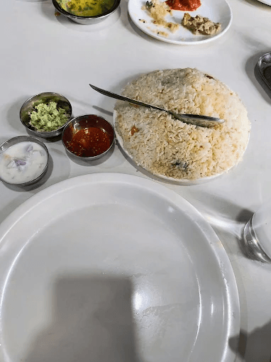 Hotel sagar kozhikode chicken dum biriyani with rice, chutneys, and a knife