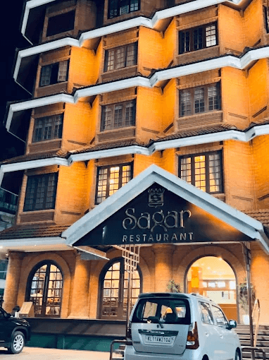 Hotel Sagar Kozhikode front view at night, with "Sagar Restaurant" sign.