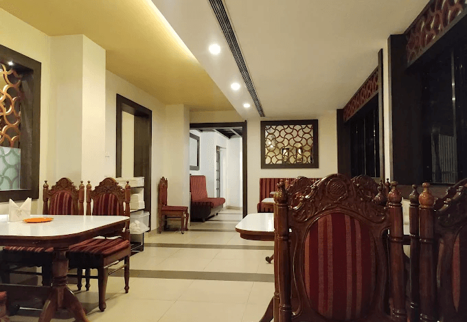 Hotel Sagar Kozhikode indoor seating with dining tables and chairs.