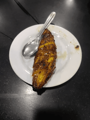 Bombay hotel kozhikode dish: Pazham nira on a white plate with a spoon